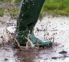 child jumping in a wet muddy puddle