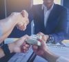 Businessman puts signature on contract at business meeting and passing money after negotiations with business partners