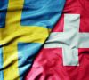 big waving national colorful flag of sweden and national flag of switzerland .