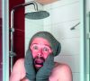 Mann mit Mütze und Handschuhen unter der Dusche