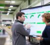 Mitarbeitende in Smart Factory vor einem Daten-Display